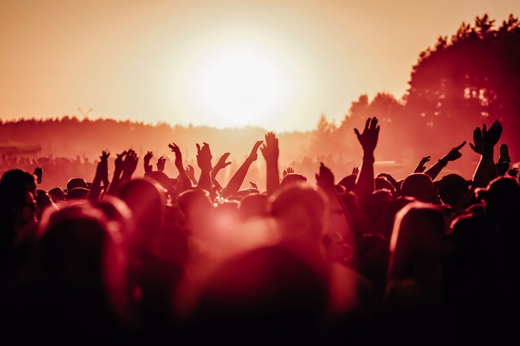 Eine Menschenmenge springt in der Abendsonne bei einem Konzert mit den Armen und Händen nach oben