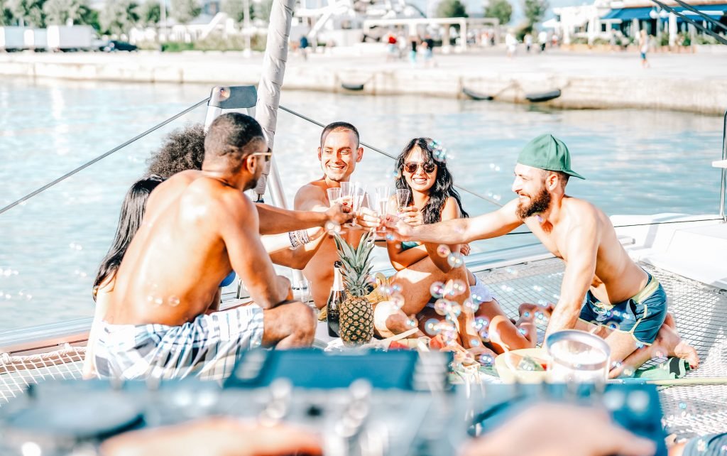 Eine Gruppe von Freunden isst gemeinsam auf einem Segelboot und stößt mit Getränken an