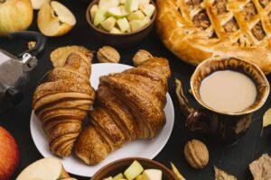 Croissants auf einem Teller, daneben eine Tasse Kaffee